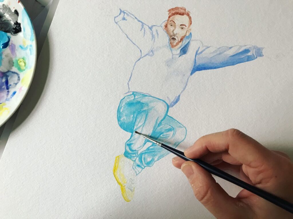 Hand mit Pinsel malt einen springenden jungen Mann in Bluejeans. links eine Malpalette